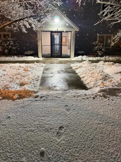 Cleared walkway to a lit entrance in the snow